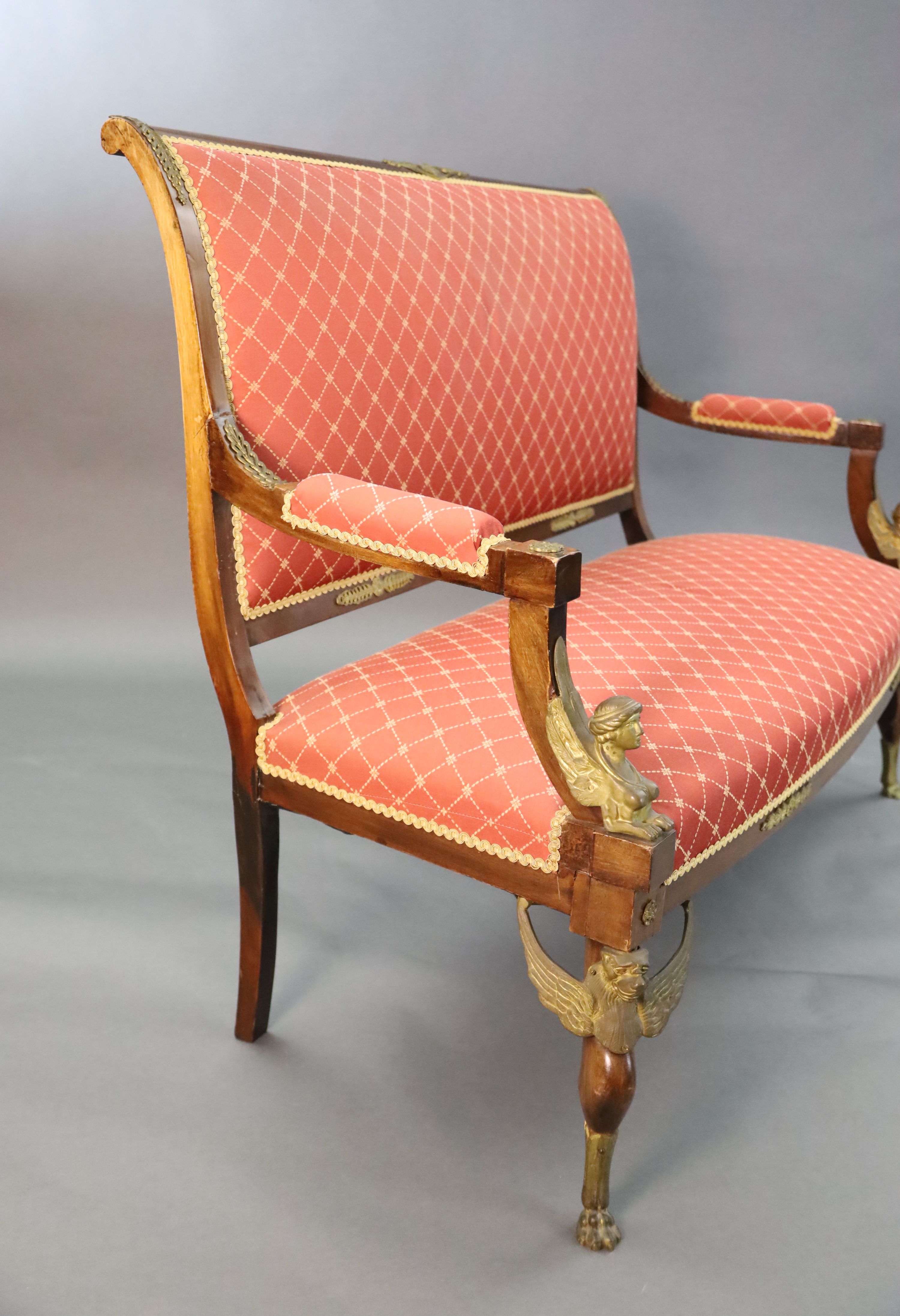 A late 19th century French Empire style ormolu mounted mahogany three piece salon suite, settee W.4ft 7in. D.2ft 5in. H.3ft 6in.